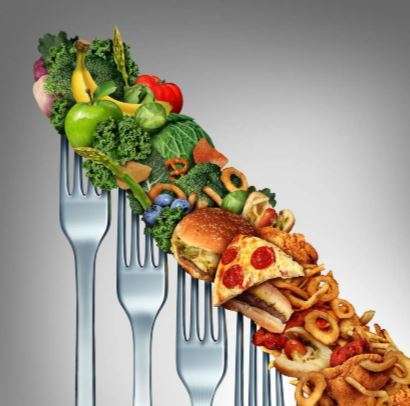 A concept image displays forks with a variety of foods. The left side features vegetarian delights like vegetables and fruits, while the right side showcases junk food such as pizza and fried items, symbolizing dietary choices.