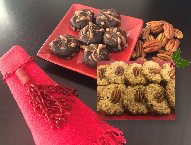 A red plate with chocolate-drizzled cookies and a pile of pecans is placed beside a red tasseled cloth. An inset shows vegan pecan-topped cookies. A small holly graphic decorates the corner, emphasizing the plant-based holiday treat.