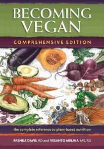 Illustration of diverse fruits and vegetables, like avocado, cabbage, pumpkin, and carrots, graces the cover of Becoming Vegan: Comprehensive Edition by dietitians Brenda Davis and Vesanto Melina. The subtitle reads the complete reference to plant-based nutrition.