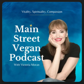 A woman with long brown hair and bright red lipstick smiles, resting her face on her hand. She graces the cover of the Main Street Vegan Podcast, with the tagline Vitality, Spirituality, Compassion set against a serene blue background, celebrating a vibrant plant-based lifestyle.