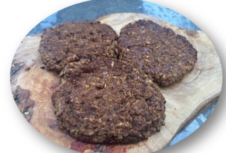 Three homemade, brown veggie burger patties resting on a wooden board, with a rustic texture and slightly uneven shapes.