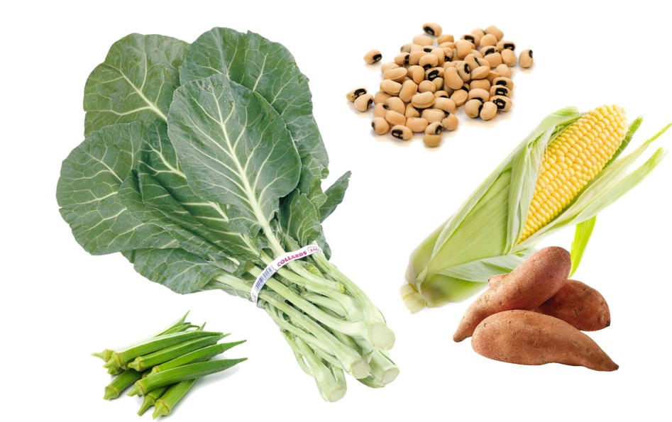 A bunch of collard greens, an ear of corn with husk partially peeled, two sweet potatoes, a pile of black-eyed peas, and a few okra pods arranged on a white background.